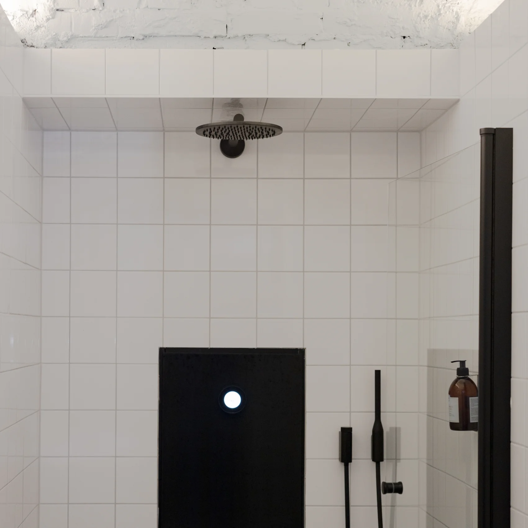Svart dusch på vitt kakel